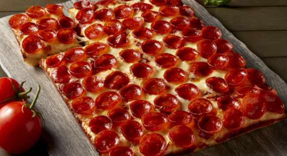 Image of pizza toppings on a square dish pizza.