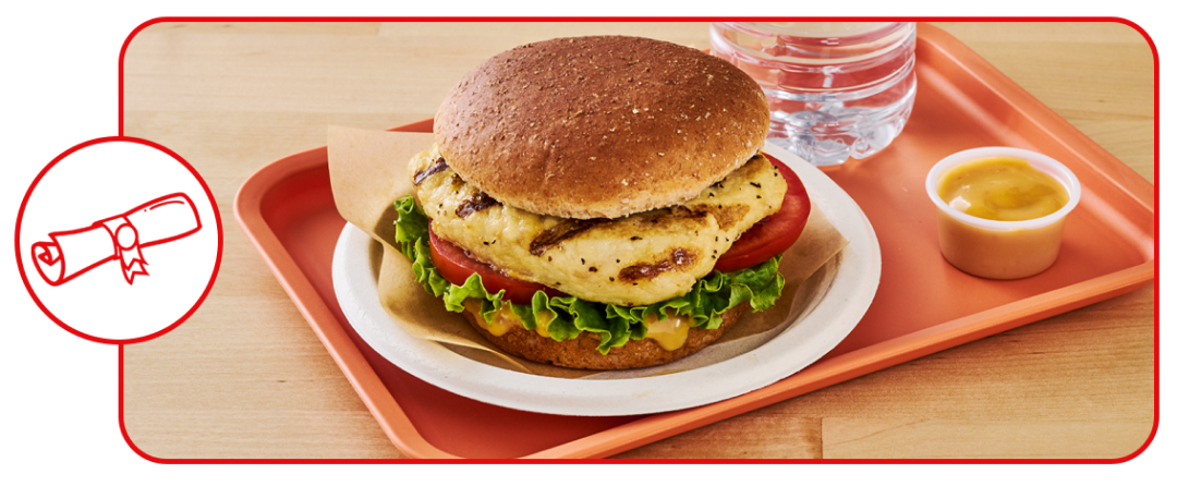 grilled chicken sandwich on tray in cafeteria setting