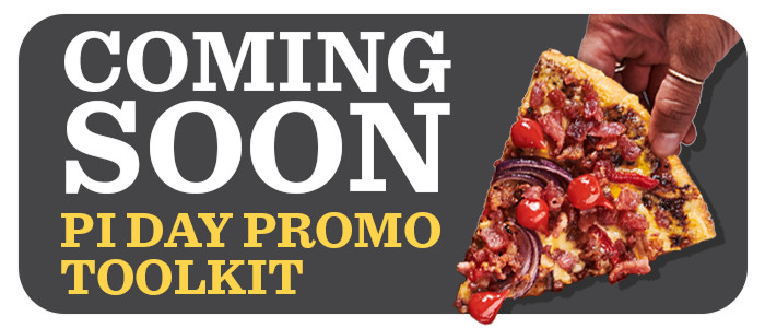 Hand holding a slice of pizza topped with crumbled beef, onions and cherry tomato halves 