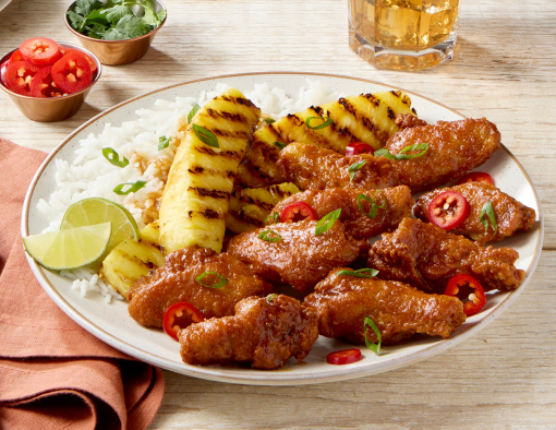 Pineapple Tamarind Wings on a white plate with a side of pineapple and rice