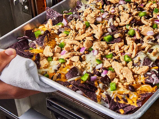 Chicken nacos with black tortilla chips, cheese and green jalapenos