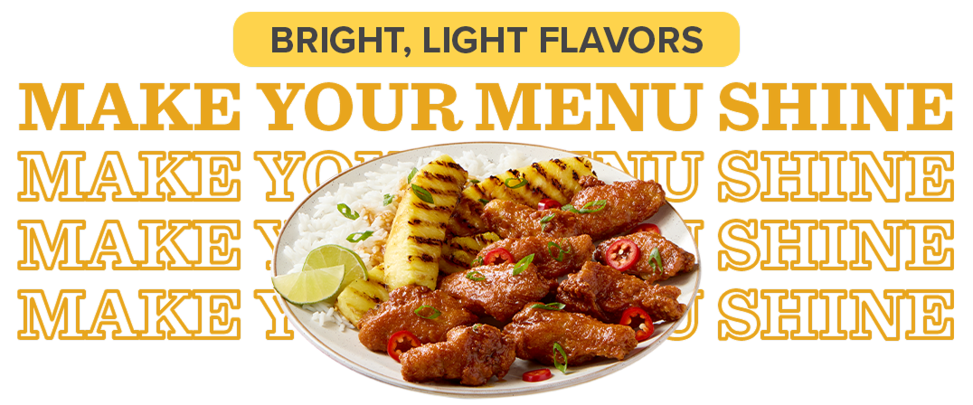 Plate of glazed wings with grilled pineapple on a bed of rice with lime wedges as garnish