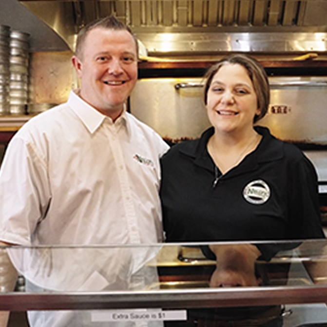 2022 Great Pizza Give Back winners, owners standing in front of their pizza oven