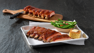 Cooked ribs plated with green breans and corn bread