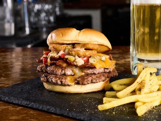 Double cheeseburger with bacon, cheese, pickle de gallo, fried pickles, and ranch on a brioche bun