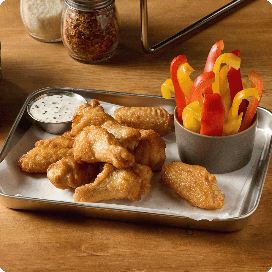 Fried wing with a side of sauce and sliced peppers