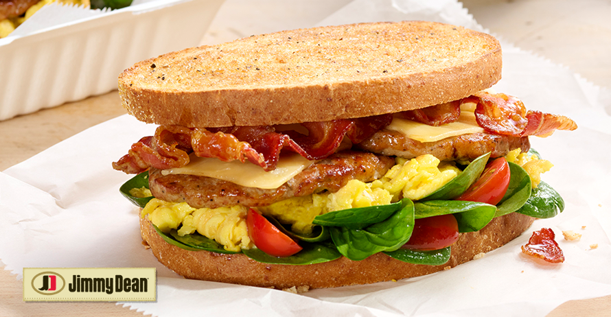 Brunchhouse Breakfast Sandwich Recipe with bacon, pork sausage, scrambled egg, smoked Gouda with grape tomatoes and baby spinach.