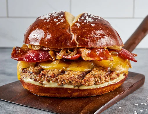 Burnt Honey Bacon and Gouda Turkey Burger on a salted pretzel bun with maple-Dijon aioli and caramelized onions