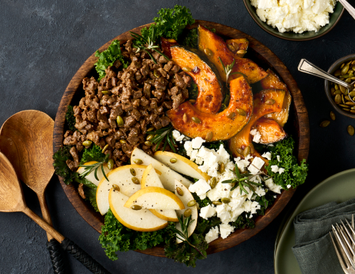 salad featuring quick stir fry beef with roasted butternut squash, toasted pumpkin seeds, feta crumbles, and Asian pear slices over a bed of wilted kale