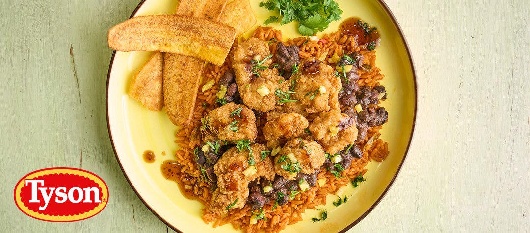 A metal bowl filled with crispy, breaded chicken chunks, sliced jalapeños, lime wedges and slaw       