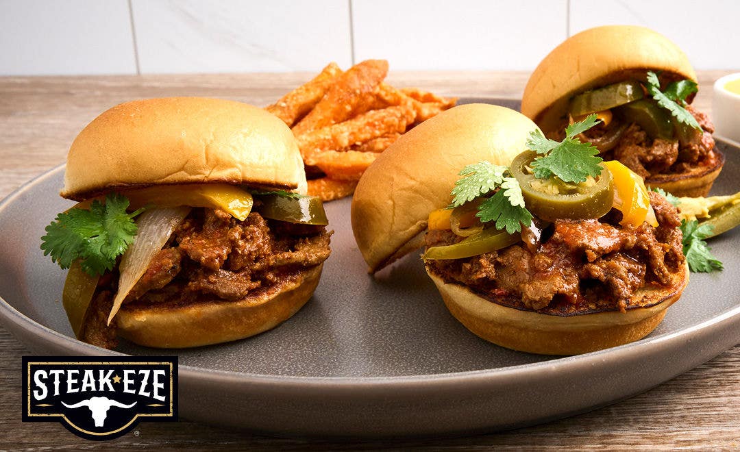 A plate with fries and three slider-style sandwiches made with sliced beef, jalapeños and sliced bell peppers  