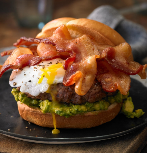 Breakfast burger with avocado, runny fried egg, and crispy bacon