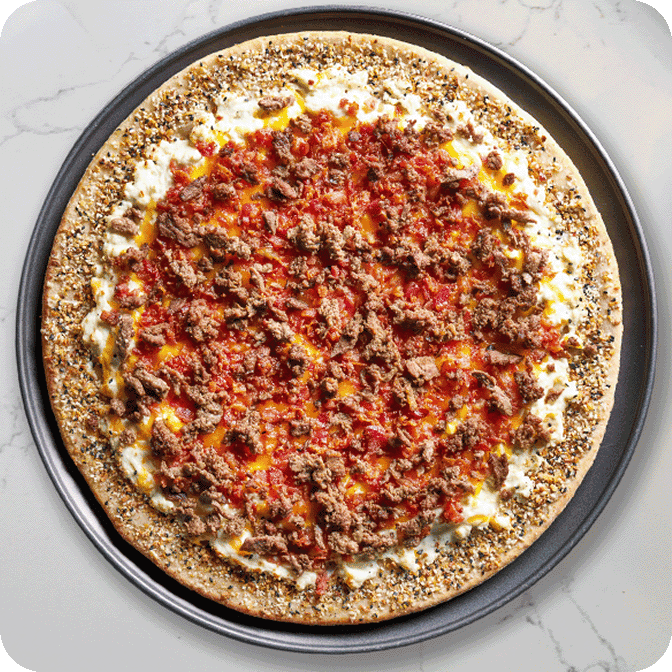 fully loaded pizza topped with egg and sliced beef on a crust with everything bagel sprinkles  
