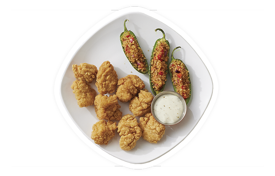 Chicken breast chunks and peppers placed on a plate with a dipping sauce