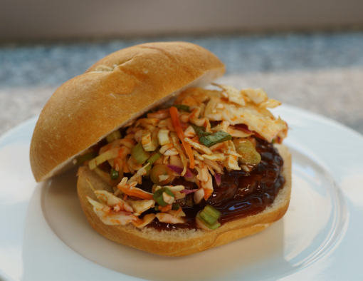 Grilled beef burger in Korean barbecue sauce glaze topped with a slaw on a whole wheat bun 