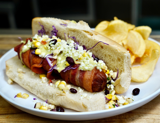 Sausage links are lathered in an avocado-tomatillo salsa and then smothered in a black bean and corn relish