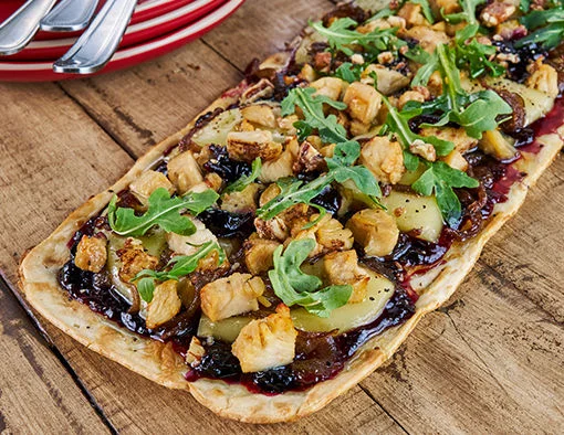 Flatbread topped with wood fire seasoned diced chicken, caramelized red onions, black currant compote, melted brie, baby arugula, and praline pecans