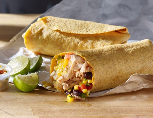 Pulled chicken, brown rice, shredded cheddar cheese, corn salad and salsa-ranch sauce in halved tortilla with lime wedges  