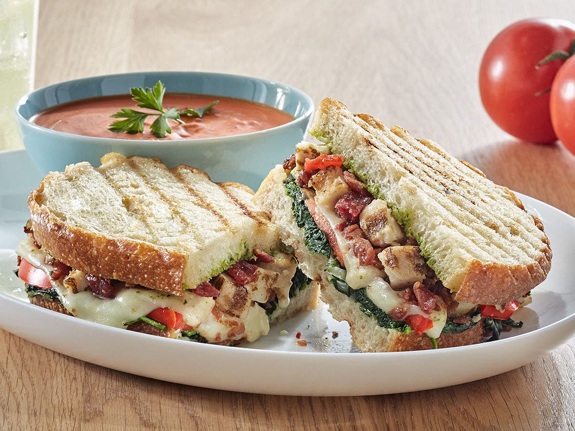 Grilled Chicken & Bacon Caprese Panini on toasted sourdough bread with mozzarella, tomato, spinach, pesto, and balsamic glaze