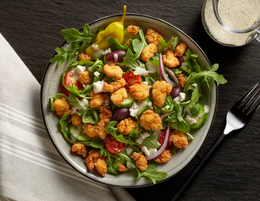 Lightly breaded Tyson® Mini Chicken Bites on a classic Mediterranean salad