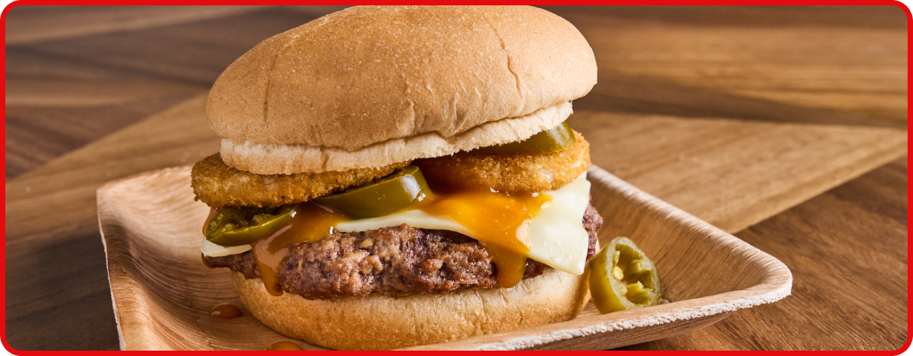 Burger topped with cheese, jalapenos, and onion rings