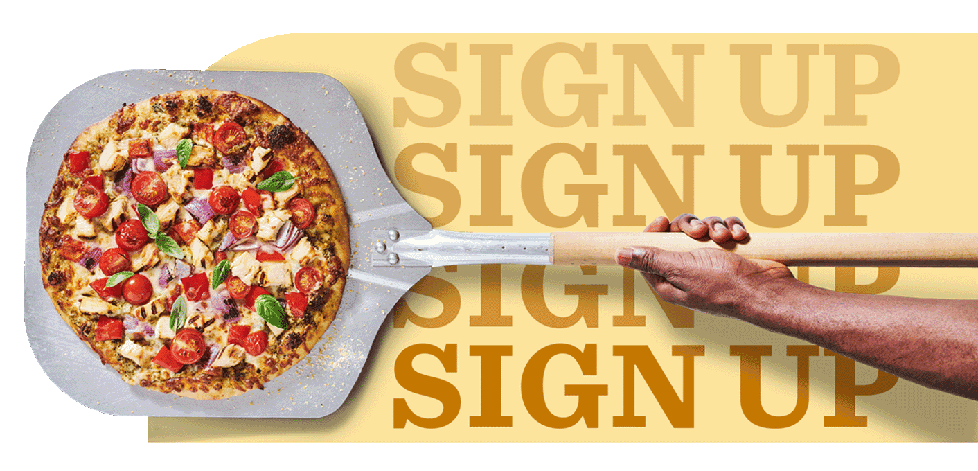 Overhead view of pizza on a pizza peel with cheese, grilled diced chicken, cherry tomatoes, onions and basil 