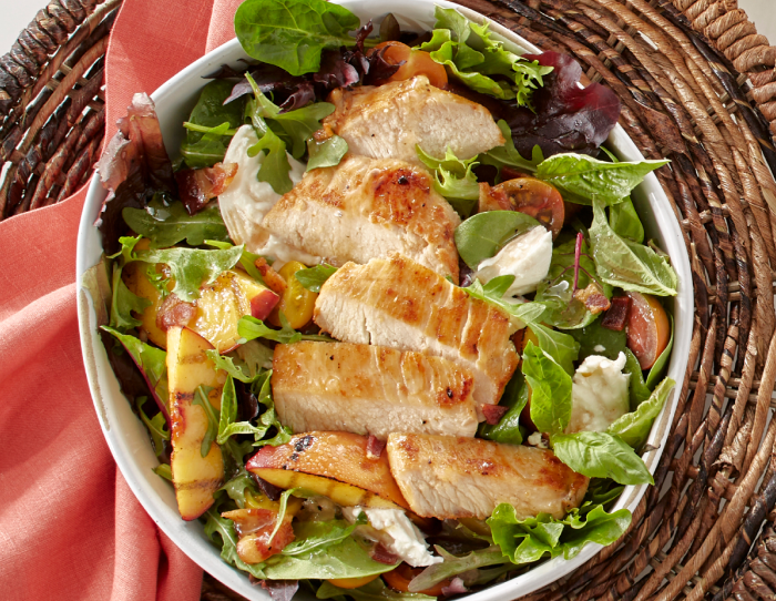 Grilled chicken topping a peach burrata salad