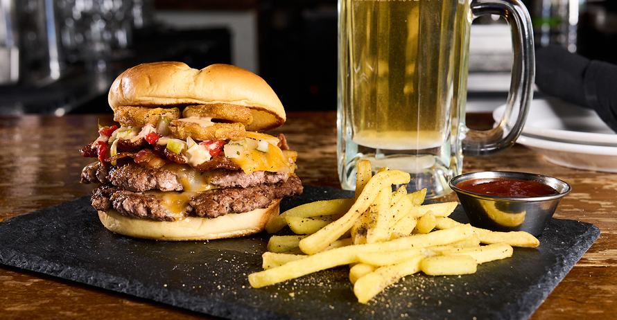 Double cheeseburger with bacon, cheese, pickle de gallo, fried pickles, and ranch on a brioche bun