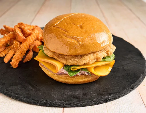 Cranberry Chicken Sandwich on a brioche bun with crispy chicken filet, cranberry ricotta, pickled squash and baby kale
