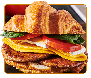 A croissant filled with two overlapping sausage patties, cheese, tomato and lettuce  