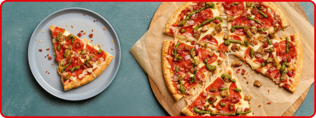 Overhead shot of pizza on cutting board and single pizza slice on plate