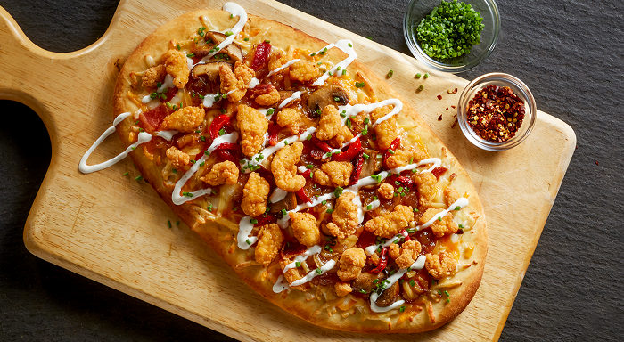 Gourmet flatbread pizza topped with mini chicken bites, vegetables, and creamy sauce