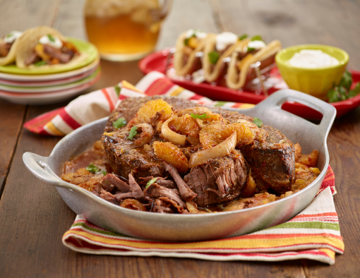 A bowl with braised beef in sauce, topped with oranges and onions