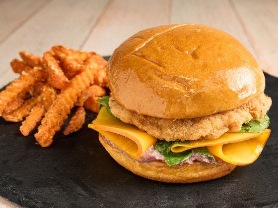 Cranberry Chicken Sandwich on a brioche bun with crispy chicken filet, cranberry ricotta, pickled squash and baby kale