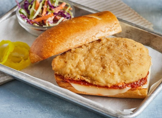 Fried cutlet sandwich with melted cheese and red sauce on a sub roll; coleslaw on the side