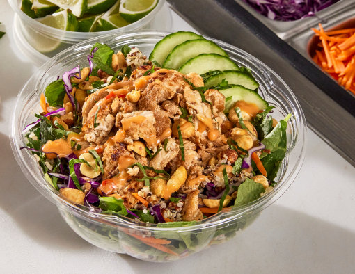 Chicken bowl with kale, cabbage, carrots, cucumbers, peanuts and a peanut lime sauce on the side