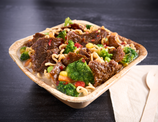 Sliced steak and vegetable mix and green onions in a clear broth over ramen noodles in a to-go container 