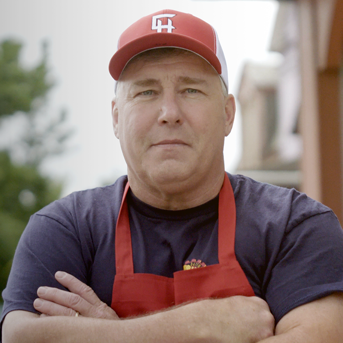 2023 Great Pizza Give Back winner owner with red hat and apron, crossing hands