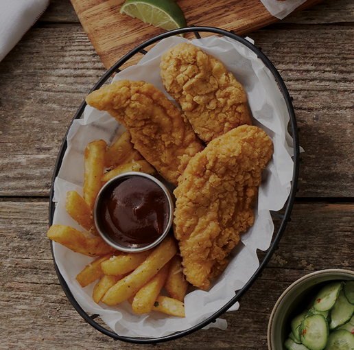 Chicken tender in a basket with fries