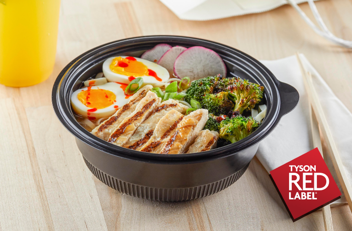 Cooked grilled chicken breasts in a bowl with eggs, broccoli and radishes