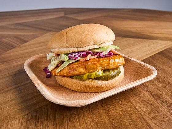 Grilled chicken in honey chipotle glaze with lemon dill slaw and dill pickles on a white wheat bun.