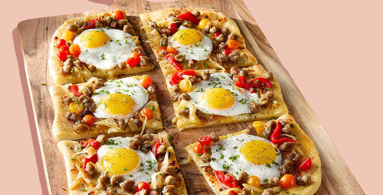 breakfast pizza topped with eggs, sausage, and peppers