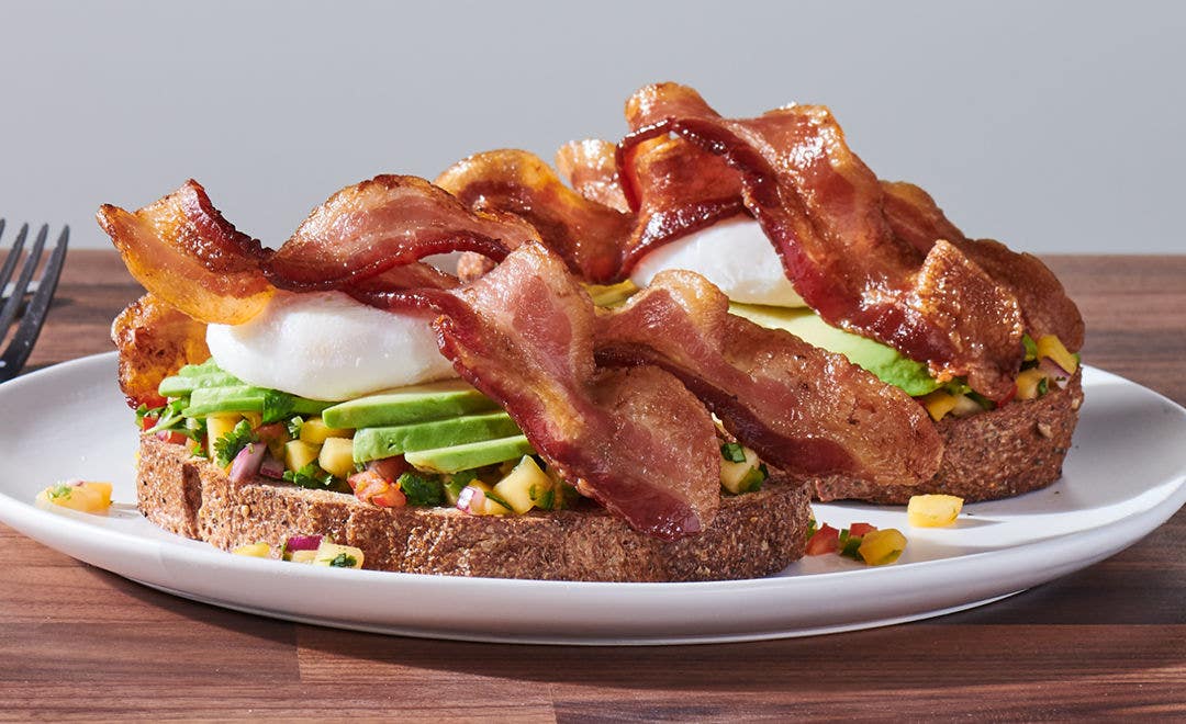 toasted sandwich topped with Pico de Gallo, sliced avocado, bacon and an over-easy egg