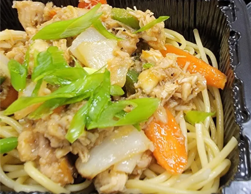 A to-go container with pulled chicken and fresh vegetables over a bed of noodles 