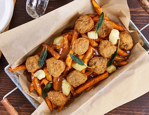 Crispy sweet potato fries topped with golden breaded steak bites, white cheese curds, sage-brown gravy, and fried sage leaves