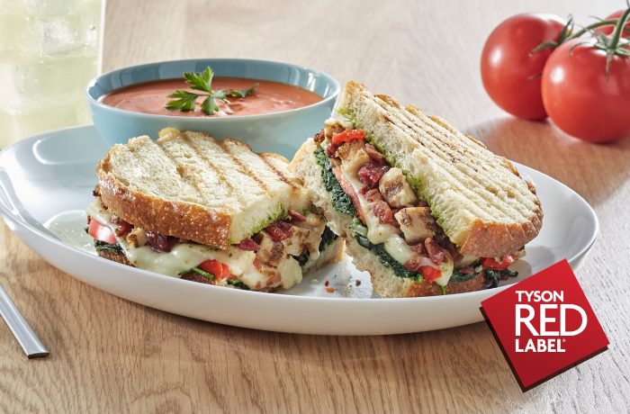 Chicken sandwich on grilled bread with side of tomato soup and 2 tomatoes