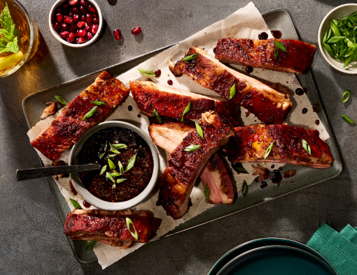 Individual pork baby back ribs in sweet pomegranate molasses glaze, topped with pomegranate seeds and scallions