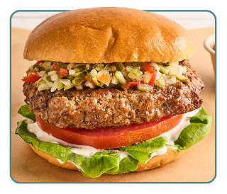A thick beef burgers on a bun with sliced tomato, lettuce and mixed relish  