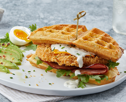 Chicken and waffle sandwich with avocado slices and boiled egg