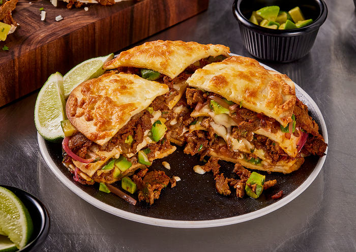 Plated steak birria tortizza with avocado and lime